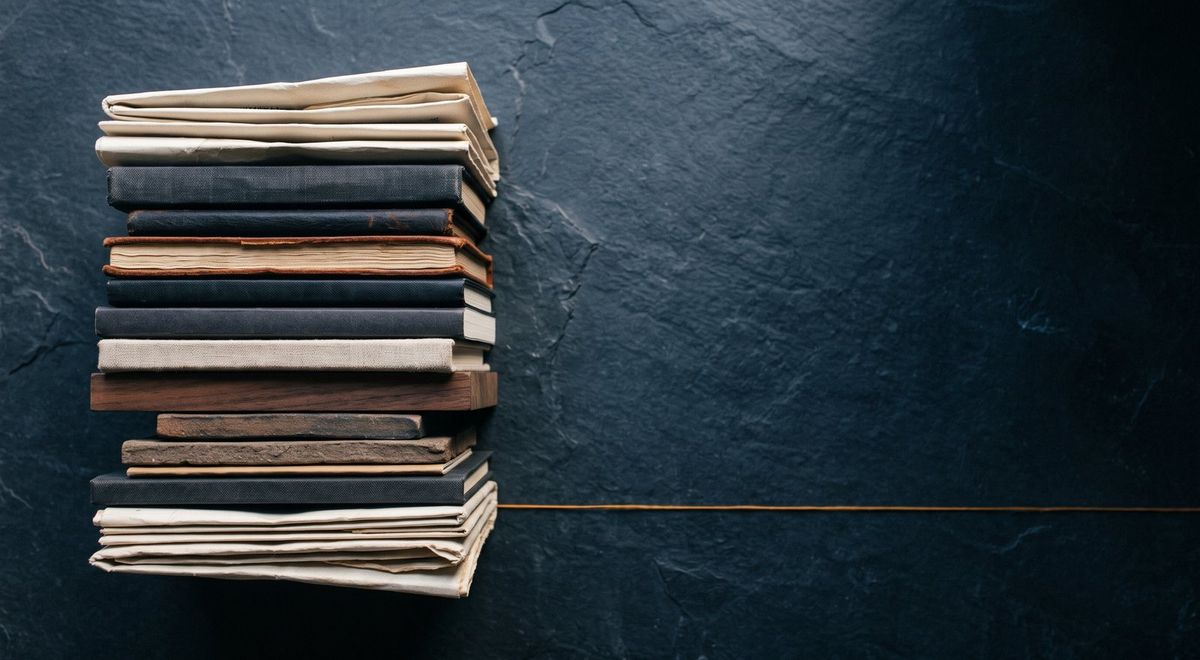 An overhead flat-lay of compact objects stacked and accumulating on one side, fading into shadow on the other.