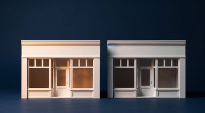 Two identical model storefronts, the left crisply lit in warm amber and the right sitting in partial shadow.